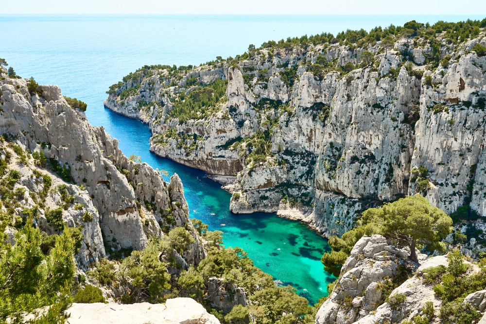 Blick in eine Calanque bei Marseille – türkisfarbenes Wasser, weiße Felswände und mediterrane Vegetation in der Sonne