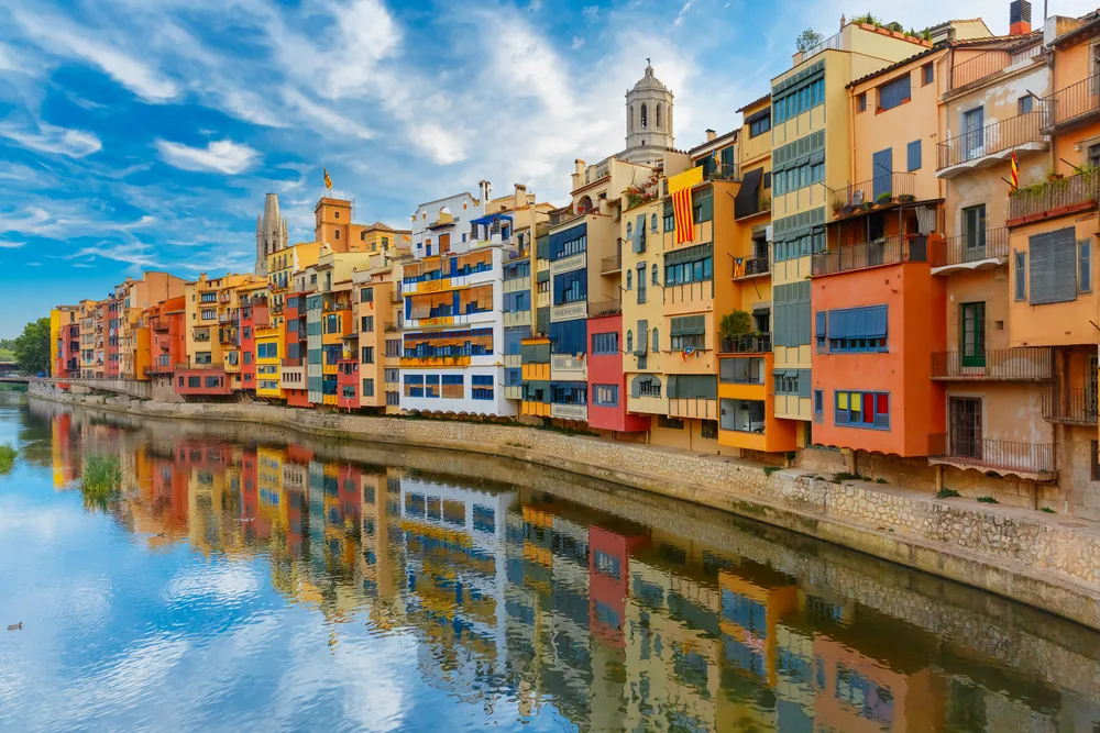 Farbenfrohe Häuserfassaden spiegeln sich im Fluss Onyar in der Altstadt von Girona